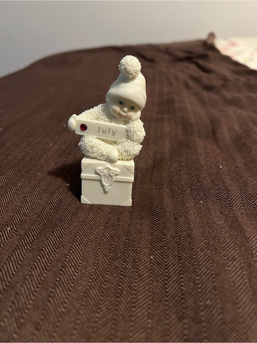 Department 56 Snowbaby Sitting On Box Holding July Sign with Red Birthstone